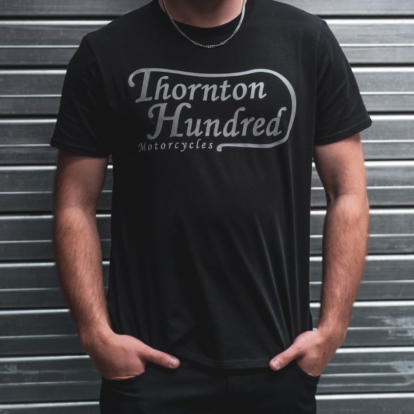 model wearing a medium black t-shirt with a logo of 'Thornton Hundred Motorcycles'